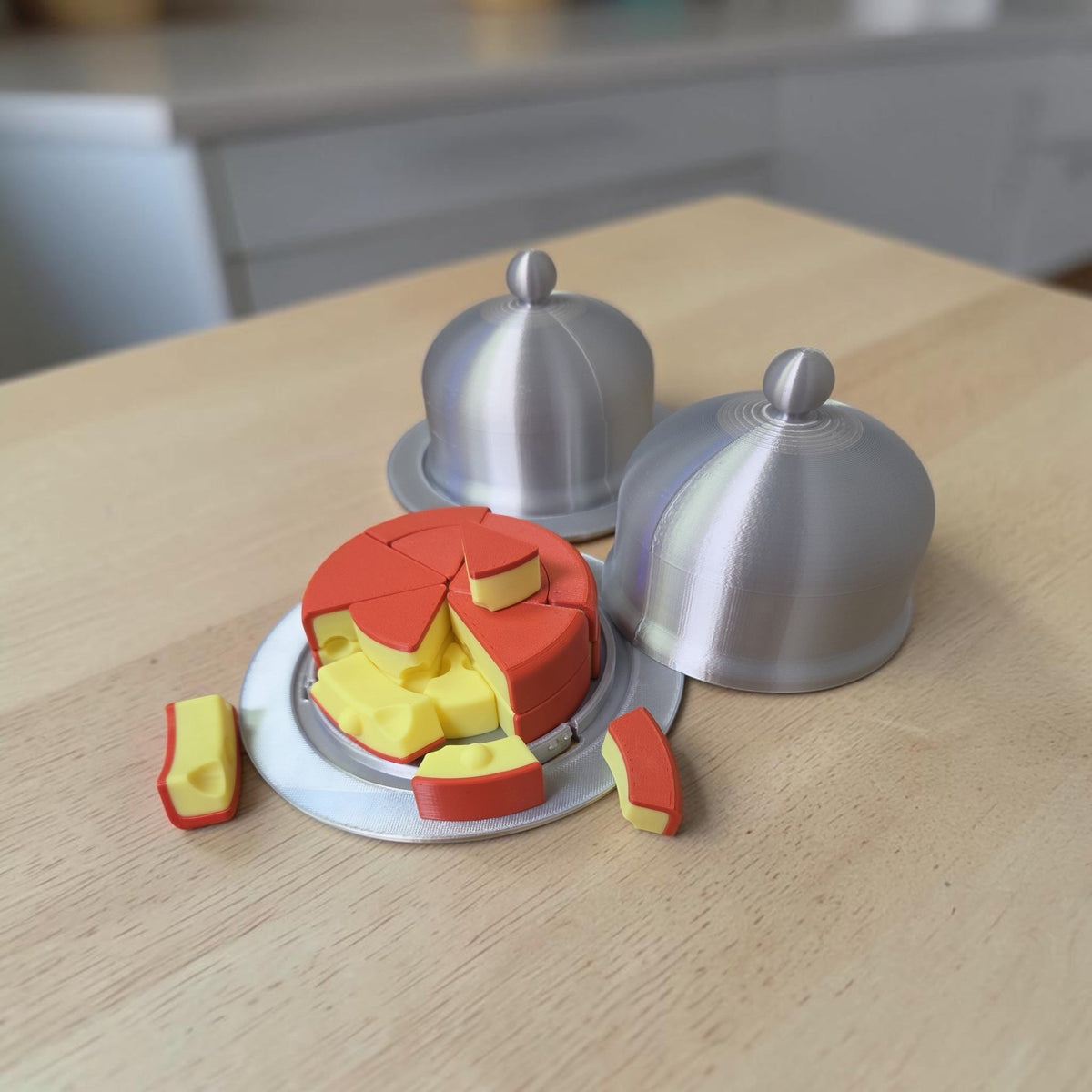 HPHobbies Layered Puzzle featuring a red and yellow cheese-shaped design with silver serving domes on a wooden table.