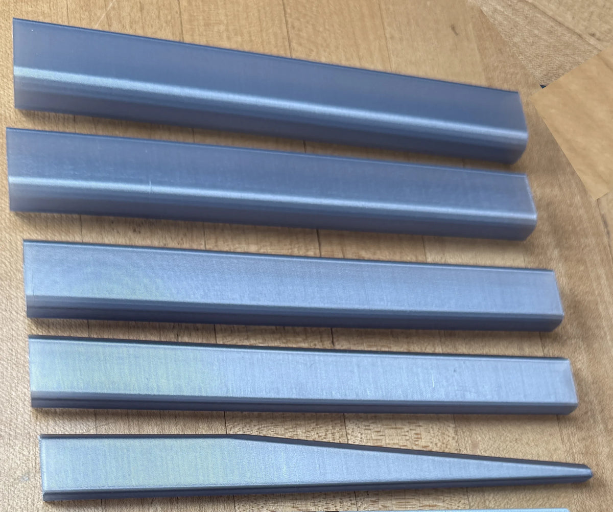 HPHobbies collapsible darksaber blade segments made of translucent grey material arranged on a wooden surface.