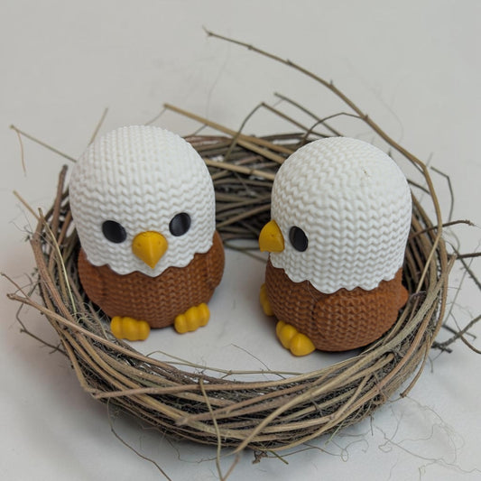 Two HPHobbies faux knit eagle figurines with white and brown textured 3D printed details sitting in a twig nest.