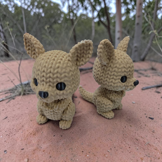 Two HPHobbies faux knit kangaroo figurines with realistic crochet-style texture standing on red dirt outdoors.