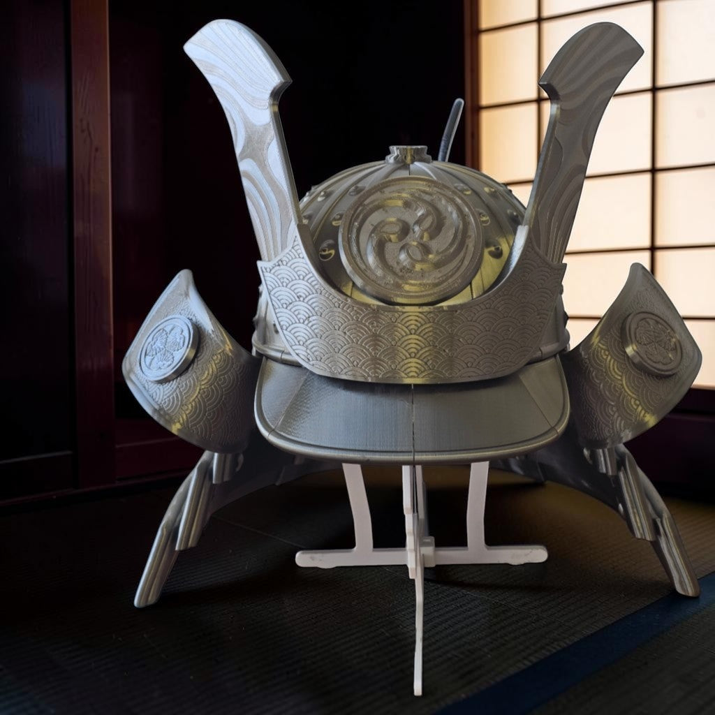HPHobbies silver Japanese Samurai Kabuto helmet replica with intricate embossed crest and wave patterns on display stand