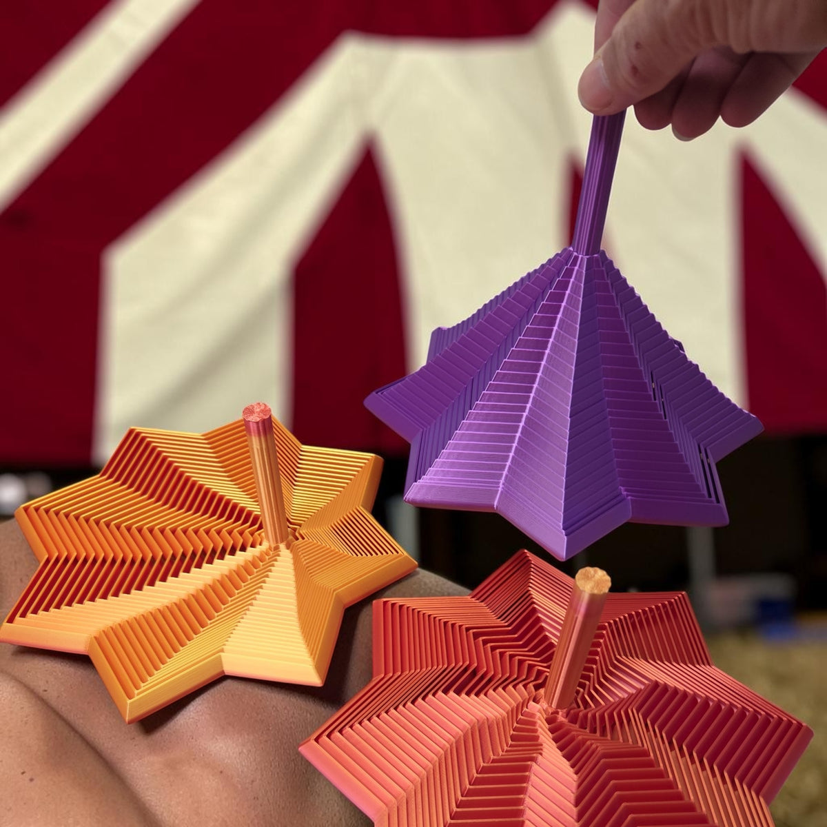 HPHobbies removable handle fidget toys in purple, orange, and red star-shaped geometric designs held by a hand.